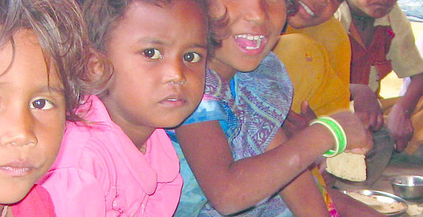 Indische Kinder, die am Boden sitzen und essen