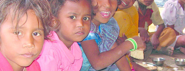 Indische Kinder, die am Boden sitzen und essen
